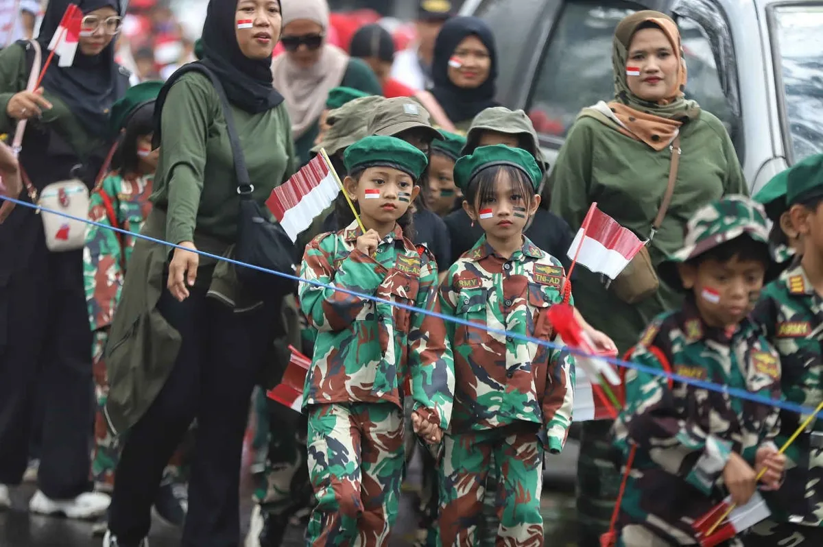 Siswa SD Negeri 067 Nilem dengan didampingi guru dan orang tua mengikuti karnaval merah putih saat melintas di Jalan Nilem, Kota Bandung, Kamis 14 Agustus 2025. (Sumber: ayobandung.com | Foto: Irfan Al-Faritsi)