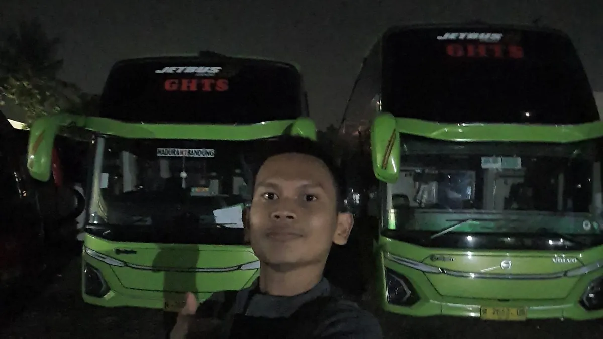 Swafoto di depan 2 armada bus Gunung Harta Transport Solutions (GHTS) malam hari di garasinya (19/11/2025) (Sumber: Dokumentasi Pribadi | Foto: Dean Rahmani)