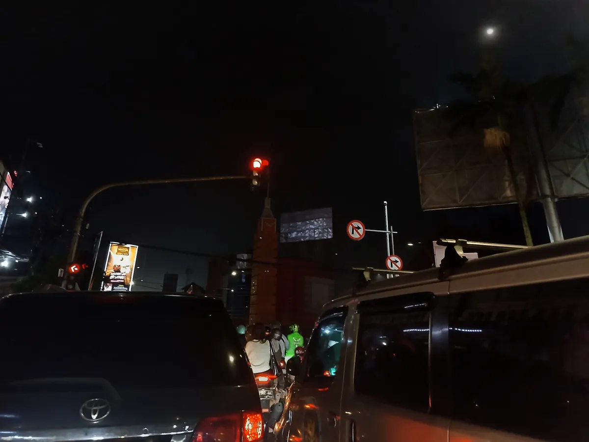 Pengendara mobil dan motor berhenti menunggu lampu lalu lintas menyala di bawah suasana malam sehabis hujan di persimpangan Tugu Simpang Lima, Kota Bandung, Kamis (4/12/2025) (Foto: Maya Angelina)