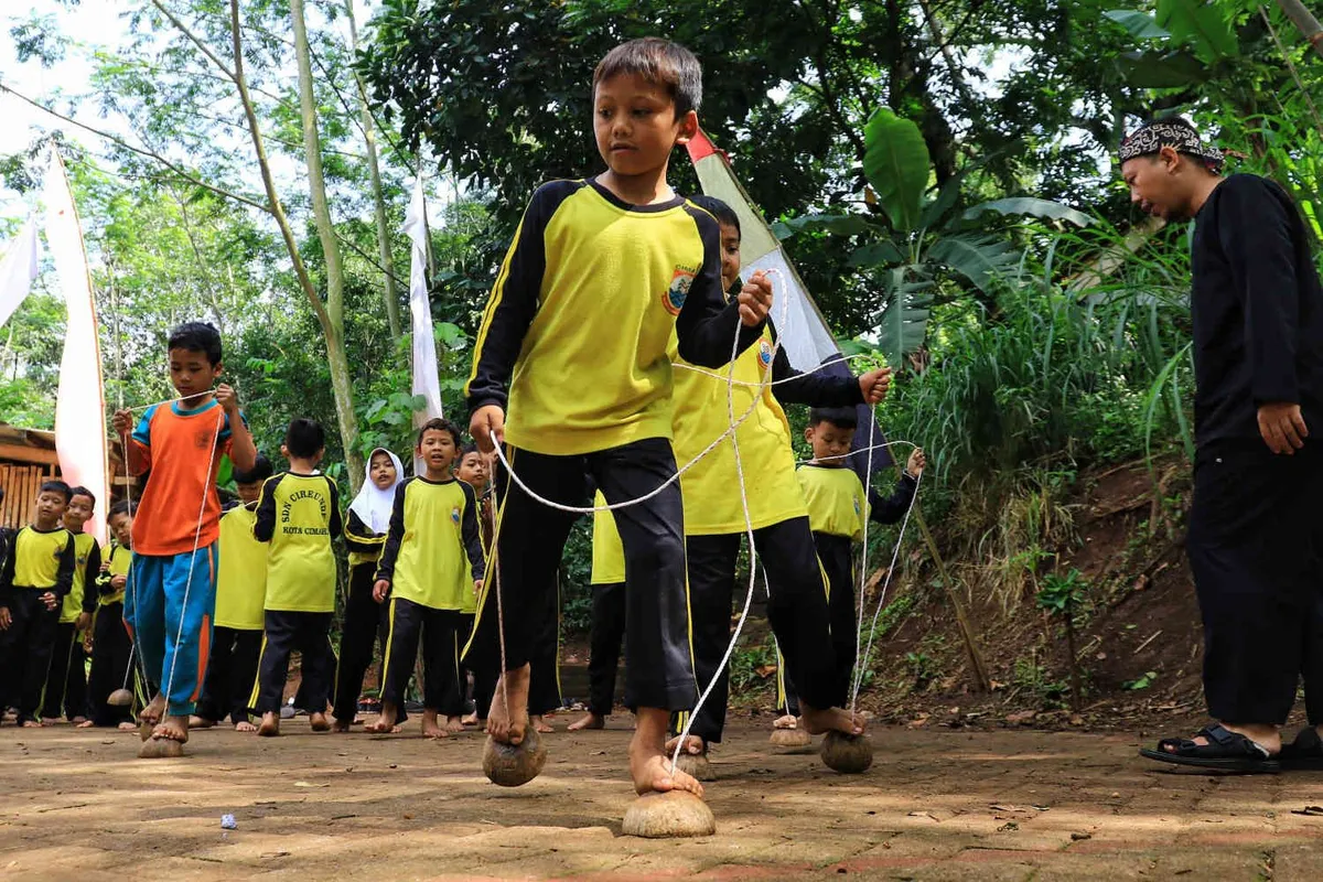 Sejumlah siswa SD Cirendeu saat bermain permainan tradisional, seperti egrang, bakiak batok, bedil jepret dan perepet jengkol, dalam rangkaian acara Festival Cirendeu 2024 di halaman sekolah SD Cirendeu, Kelurahan Leuwigajah, Kecamatan Cimahi Selatan, Kota Cimahi, Sabtu 7 Desember 2024. (Sumber: ayobandung.com | Foto: Irfan Al-Faritsi)