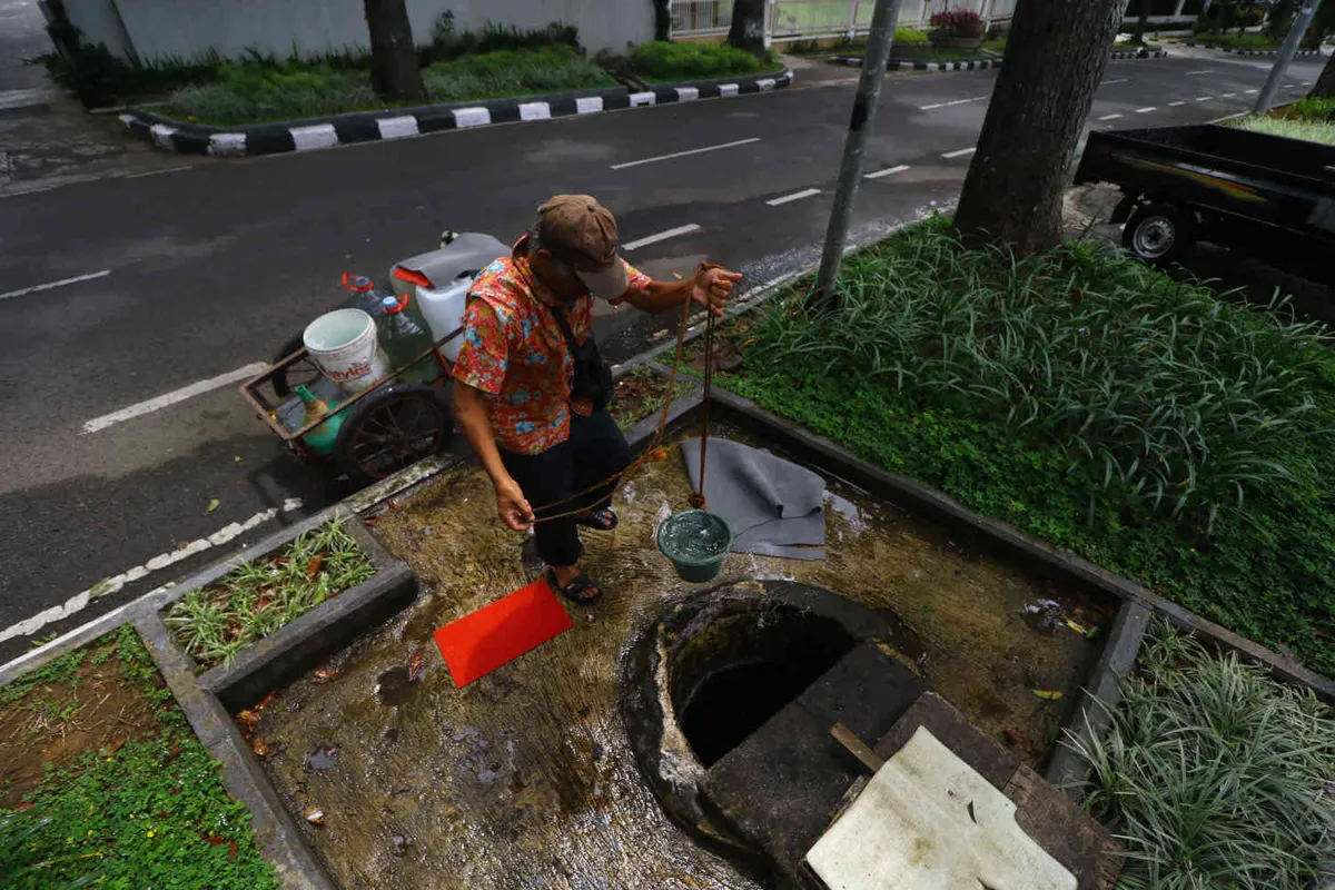 Warga mengambil air sumur yang berada di trotoar Jalan Cipaganti, Kelurahan Pasirkaliki, Kecamatan Cicendo, Kota Bandung. (Sumber: Ayobandung | Foto: Irfan Al Faritsi)