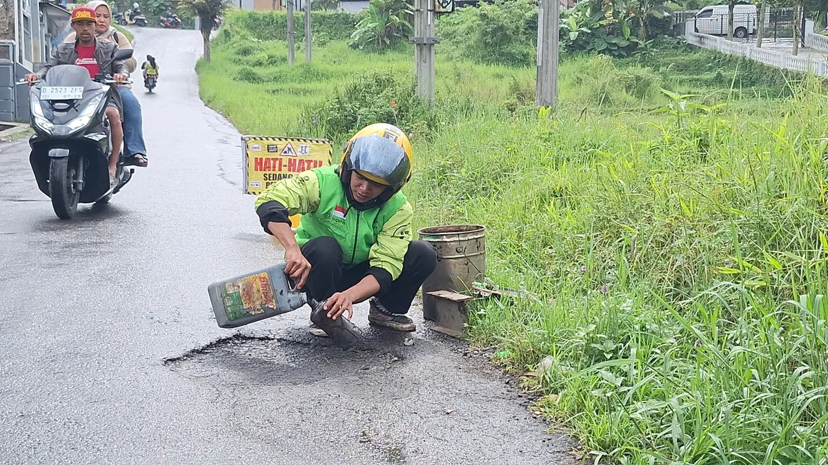 Hasan Fiidel, ojol asal Kabupaten Bandung memperbaiki jalan rusak tanpa duit pemerintah. (Sumber: Ayobandung | Foto: Mildan Abdalloh)