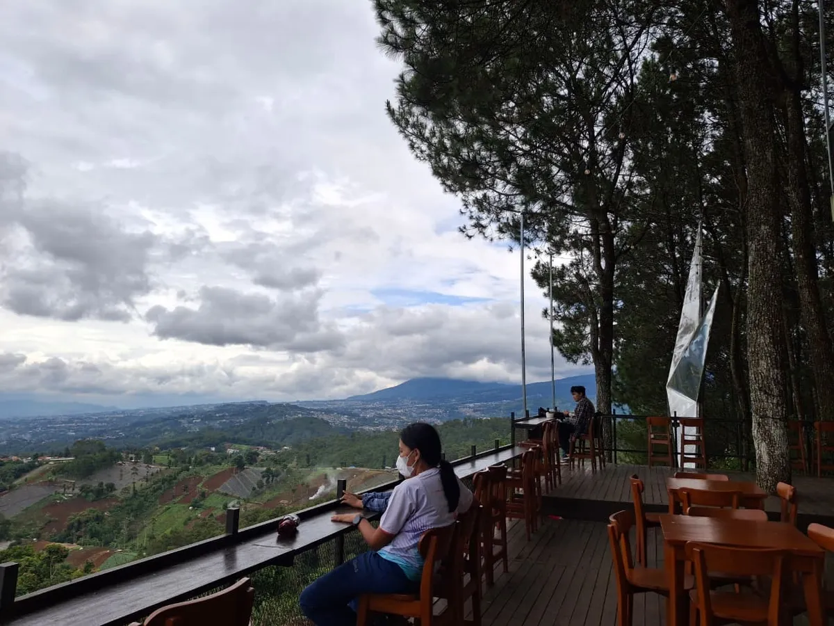 Pengunjunng menikmati pesanan di tengah teduhnya pohon pinus dengan pemandangan kota Bandung, (08-11-2025).