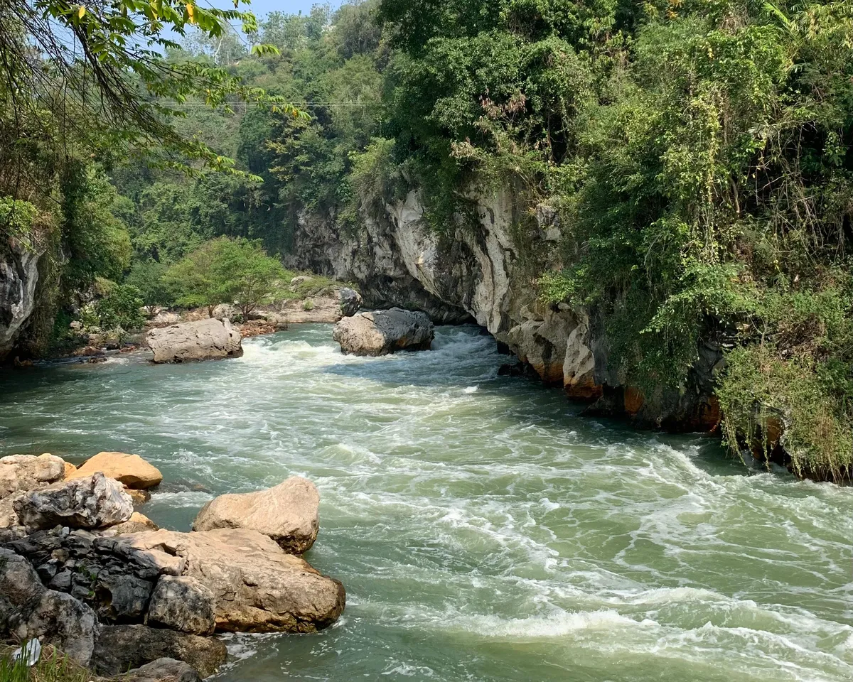 Aliran sungai berarus deras yang mengalir di antara tebing batu dan pepohonan hijau. (Sumber: Nada | Foto: Nada)
