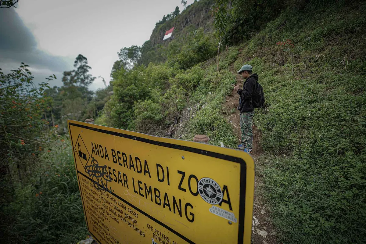 Warga melintas di dekat rambu zona Sesar Lembang di kawasan Gunung Batu, Lembang, Kabupaten Bandung Barat. (Sumber: Ayobandung | Foto: Kavin Faza)