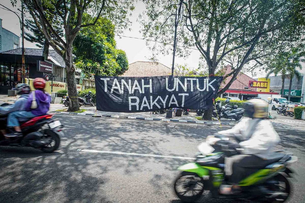 Warga melintas di dekat bentangan spanduk perlawanan warga Dago Elos di Pengadilan Negeri (PN) Bandung, Jalan LL. RE. Martadinata, Kota Bandung. (Sumber: Ayobandung | Foto: Kavin Faza)