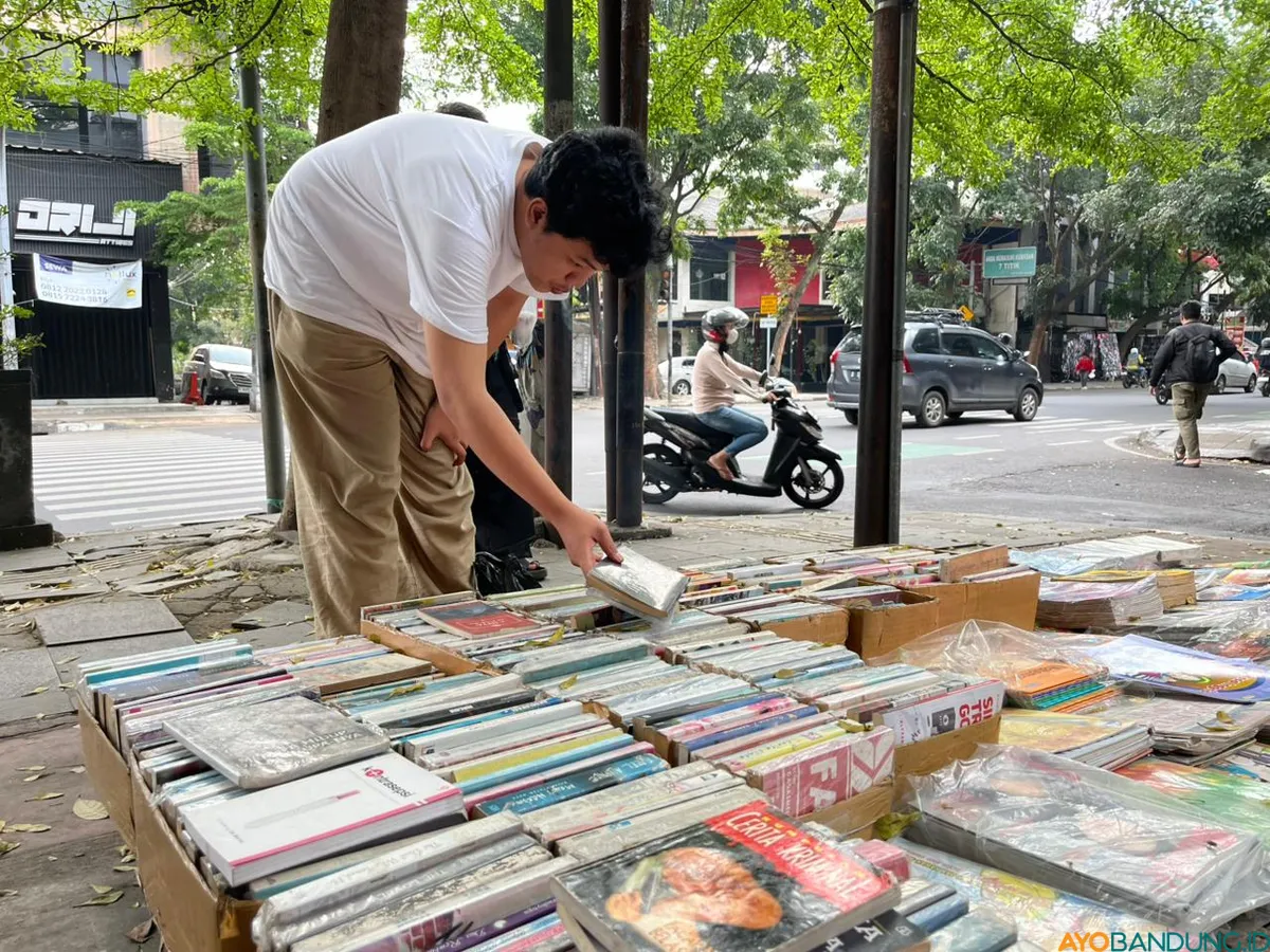Seorang pembeli tampak asyik memilih buku, mencari bacaan lama yang sulit ditemukan di toko buku modern. (Sumber: ayobandung.id | Foto: Ilham Maulana)