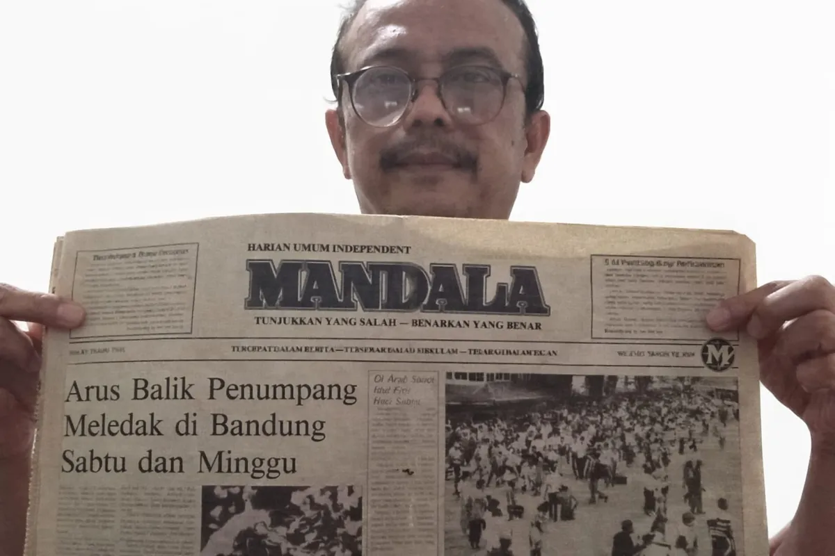 Penulis memperlihatkan surat kabar MANDALA yang memuat laporan tentang arus urbanisasi menuju Kota Bandung pada akhir dekade 1980-an. (Sumber: Dokumentasi Penulis)