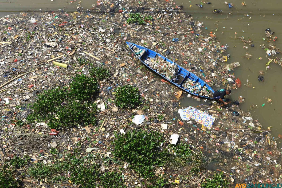 Seorang warga mengumpulkan sampah plastik berupa botol dan gelas menggunakan perahu di bawah jembatan Babakan Sapan (BBS) Batujajar, Kabupaten Bandung Barat (KBB), Jumat 30 Juni 2025. (Sumber: ayobandung.id | Foto: Irfan Al- Faritsi)