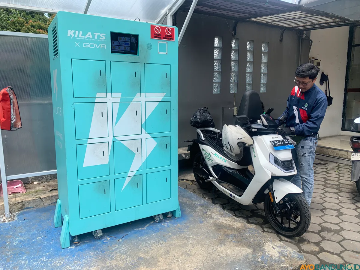 Rizki Ahmad sedang melakukan pengisian baterai motor listrik di Kantor Pos Ujung Berung Kota Bandung, pada Kamis, 9 April 2026. (Sumber: ayobandung.id | Foto: Toni Hermawan)