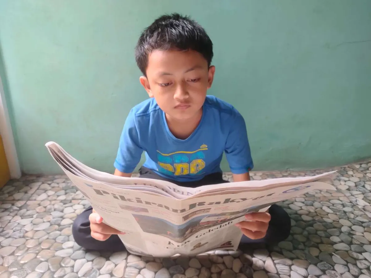 Aa Akil, anak kedua tengah asyik baca koran, Sabtu (4/4/2026) (Sumber: Istimewa | Foto: IBN GHIFARIE)