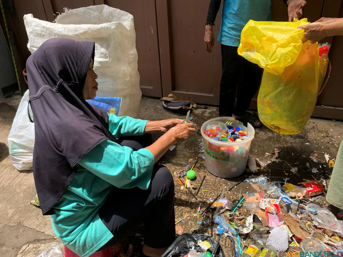 Seorang ibu tim Perelek Sampah di Kecamatan Cibogo sedang membersihkan dan memisahkan tutup botol plastik. (Sumber: ayobandung.id | Foto: Halwa Raudhatul)