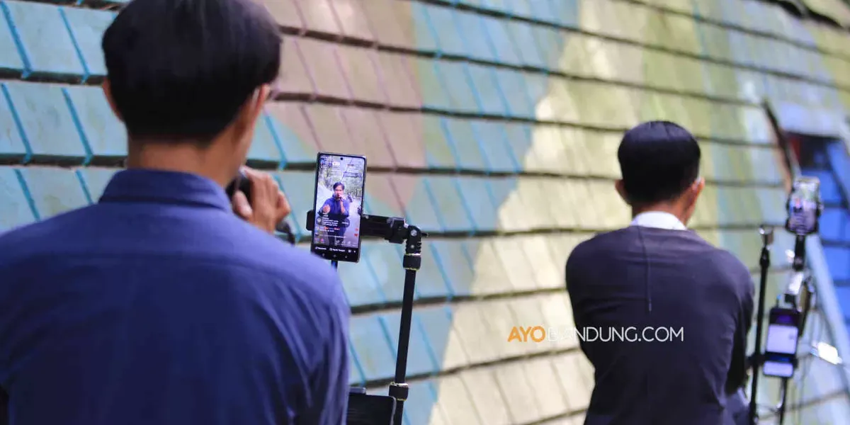 Konten kreator TikTok bernyanyi secara daring menggunakan smartphone (telepon pintar) di Jalan Babakan Siliwangi, Kota Bandung (Sumber: Ayobandung.com | Foto: Irfan Al-Faritsi)