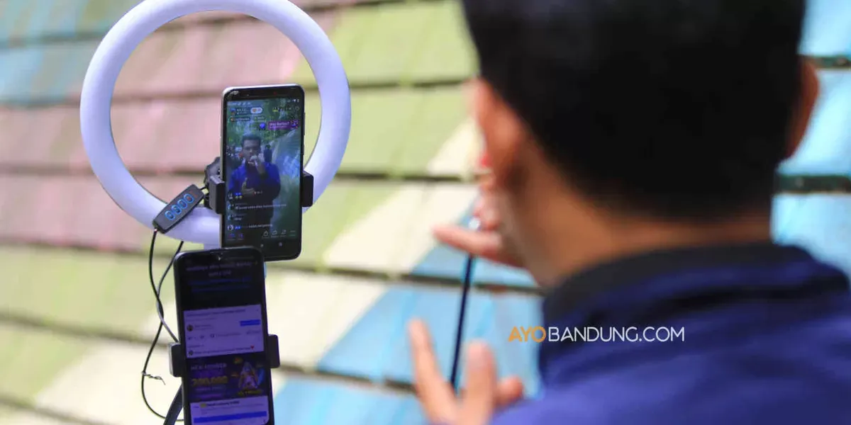 Konten kreator TikTok bernyanyi secara daring menggunakan smartphone (telepon pintar) di Jalan Babakan Siliwangi, Kota Bandung (Sumber: Ayobandung.com | Foto: Irfan Al-Faritsi)