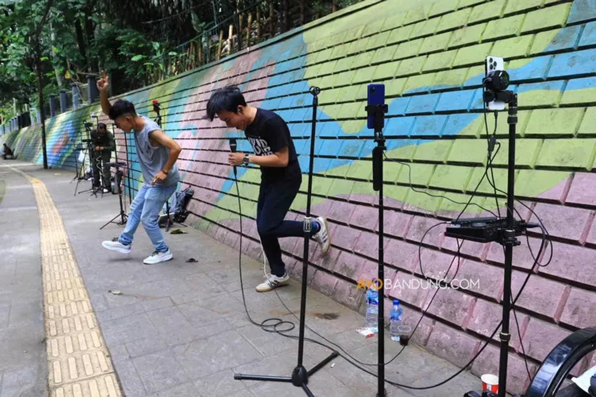 Konten kreator TikTok bernyanyi secara daring menggunakan smartphone (telepon pintar) di Jalan Babakan Siliwangi, Kota Bandung (Sumber: Ayobandung.com | Foto: Irfan Al-Faritsi)