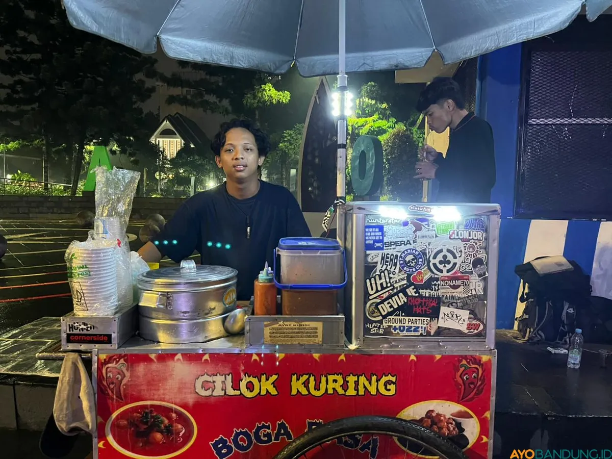 Raja Saut Martua Sinaga tetap berjualan cilok seperti biasa di kawasan Dago, Bandung, sambil membuka akses baca gratis bagi pengunjung yang datang. (Sumber: ayobandung.id | Foto: Ilham Maulana)