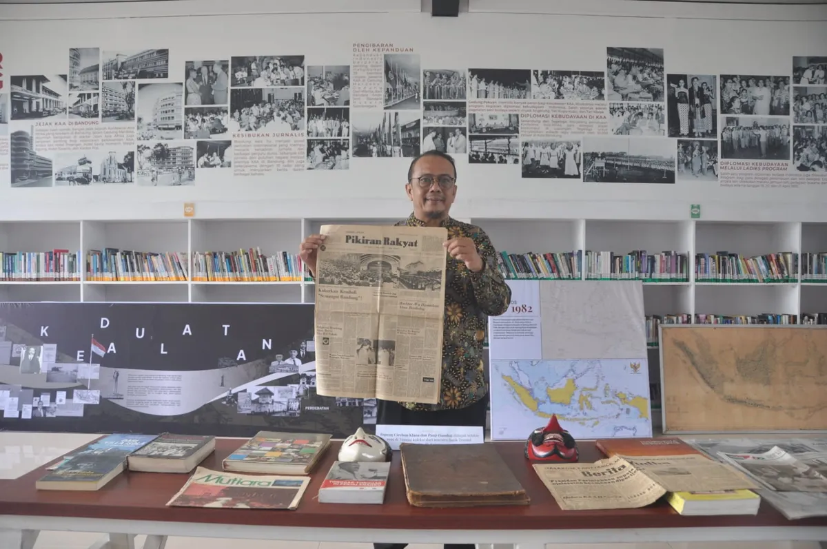 Penulis berpose bersama koleksi media cetak lawas terkait Konferensi Asia Afrika yang turut ditampilkan dalam pameran Bandung Milestone. (Sumber: Dokumentasi Penulis | Foto: Kin Sanubary)
