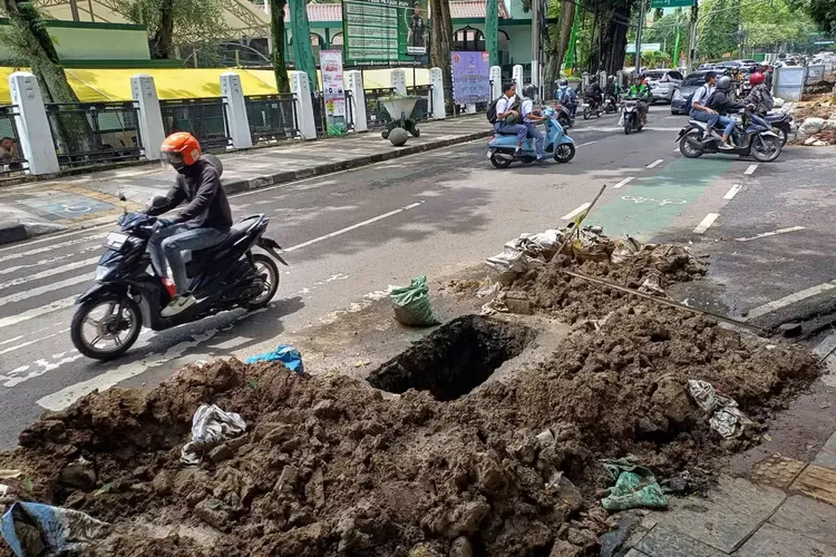 Pengendara melintas di dekat galian kabel optik di Jalan Aceh, Kota Bandung, Jumat 6 Desember 2024. (Sumber: Ayobandung.id | Foto: Irfan Al-Faritsi)