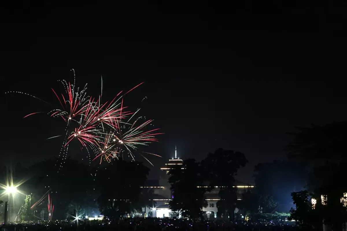 Ribuan masyarakat menyaksikan aksi kembang api saat malam tahun baru 2024 di Lapangan Gasibu, Kota Bandung. (Sumber: Ayobandung.com | Foto: Magang Foto/Rasyad Yahdiyan)