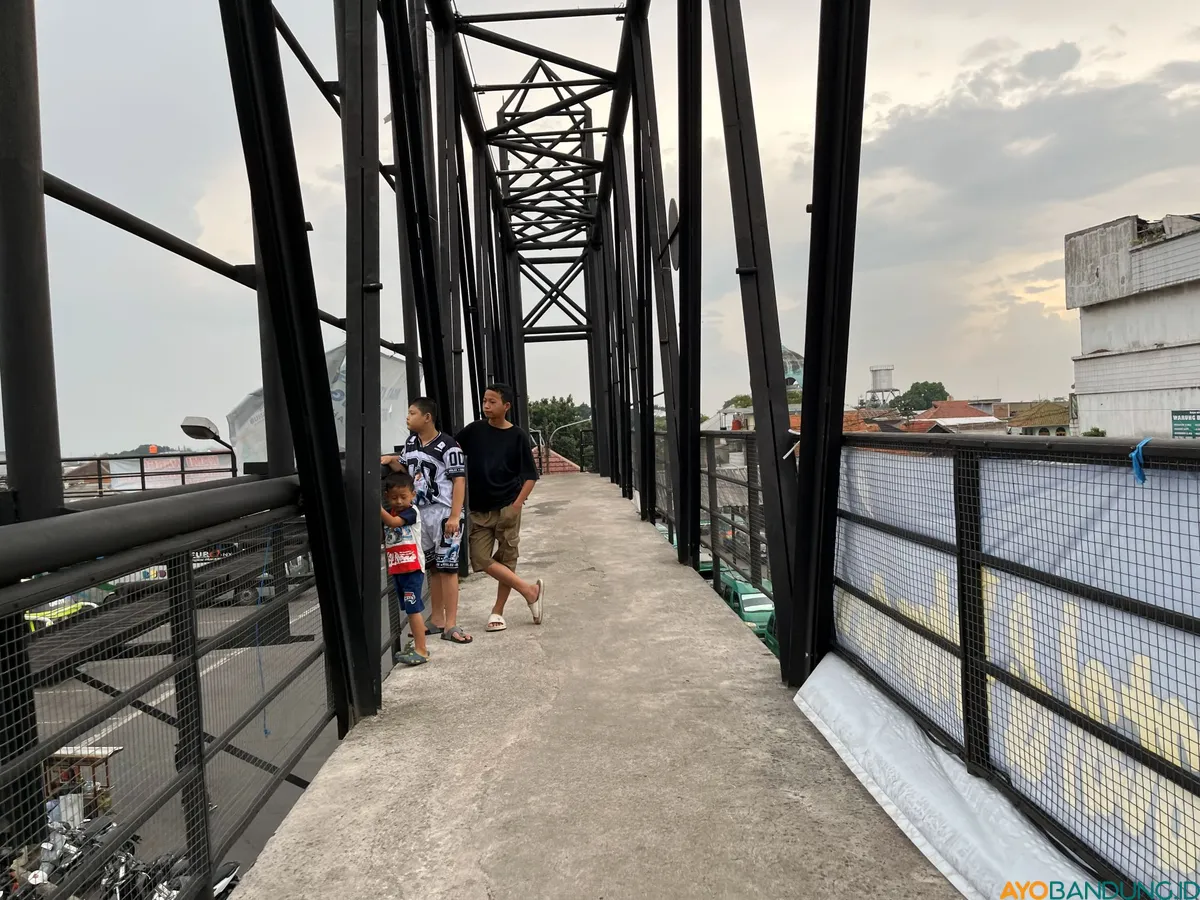 Anak-anak menonton kendaraan yang melintas dari Jembatan Penyebarangan Orang (JPO) Terminal Cicaheum. (Sumber: ayobandung.id | Foto: Ilham Maulana)