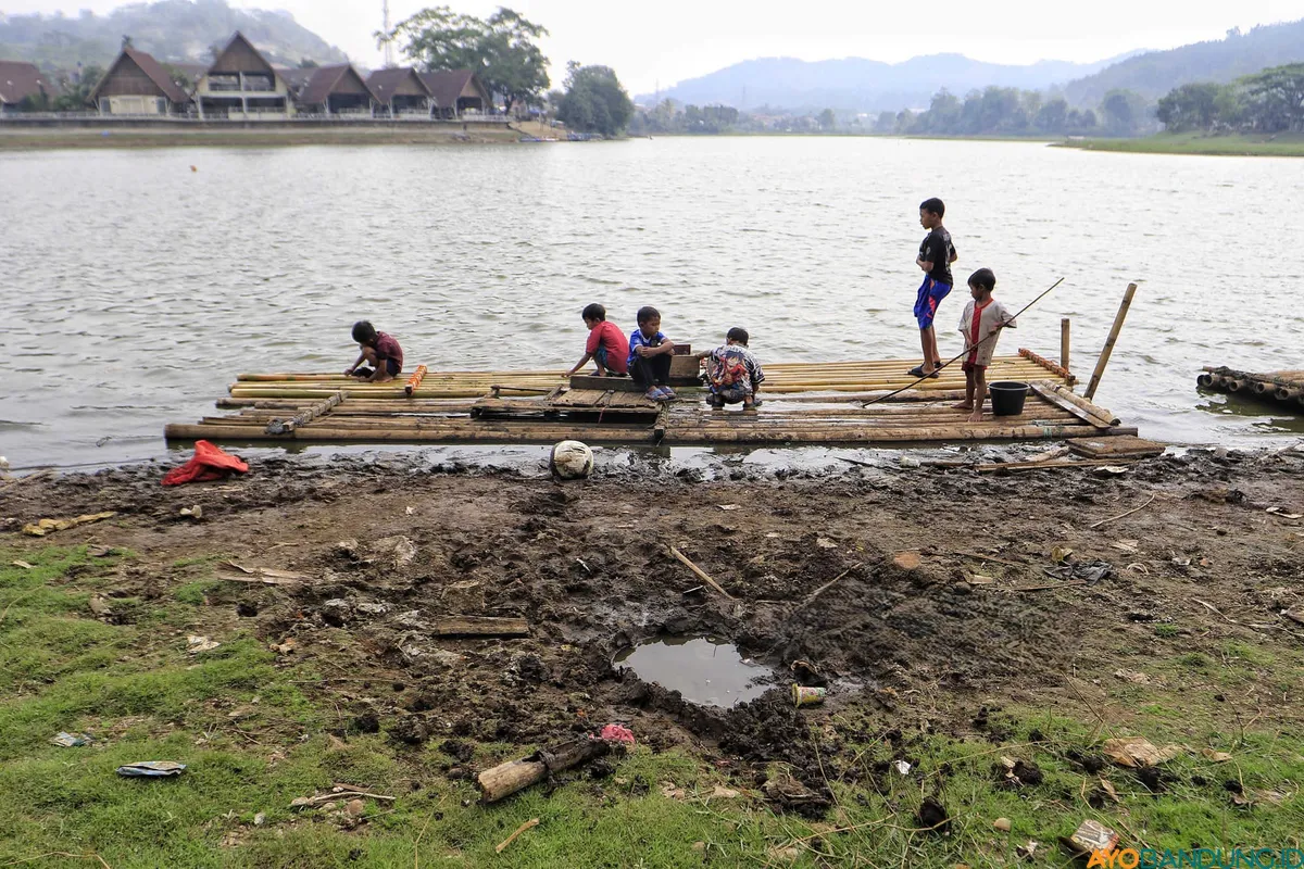 Surutnya air Situ Ciburuy di tengah kemarau panjang tak hanya berdampak pada irigasi warga, tetapi juga mengubah dasar danau menjadi ruang bermain bagi anak-anak sekitar. (Sumber: ayobandung.id | Foto: Irfan Al Faritsi)