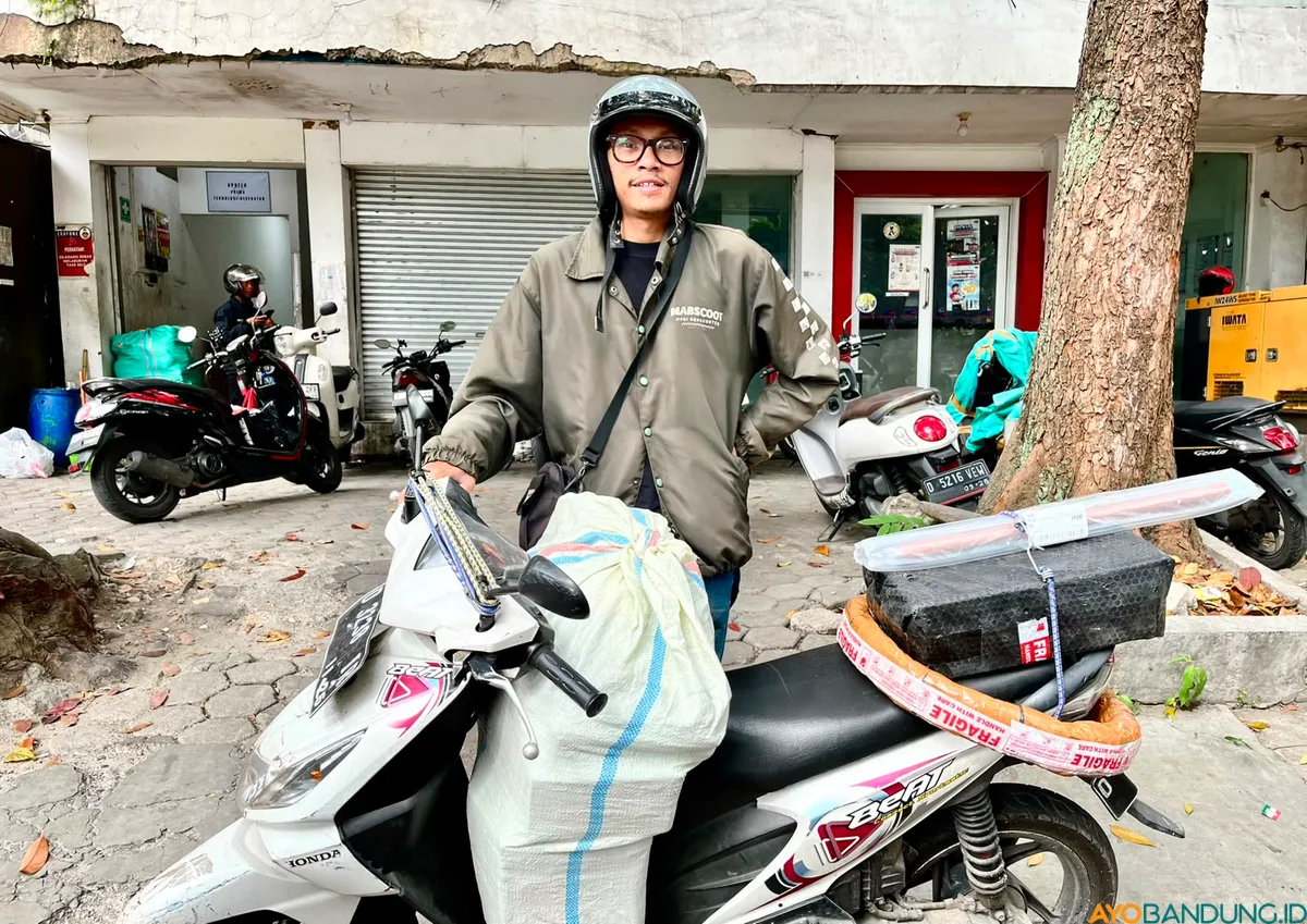 Dedikasi tanpa batas Hasan Al Nazhari, kurir JNE Bandung yang tetap tegar menjaga amanah pengiriman paket meski sempat menjadi korban pembegalan. (Sumber: ayobandung.id | Foto: Arif Budianto)