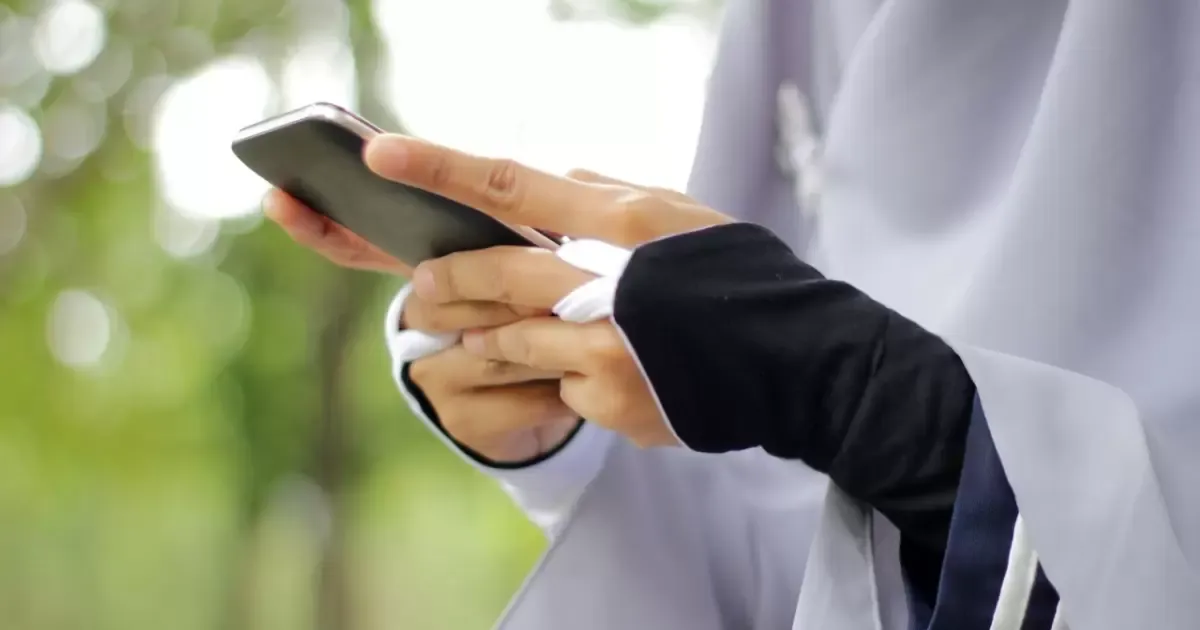 Ilustrasi seorang muslimah mengecek smartphone miliknya. (Sumber: Getty Images/Fajrul Islam)