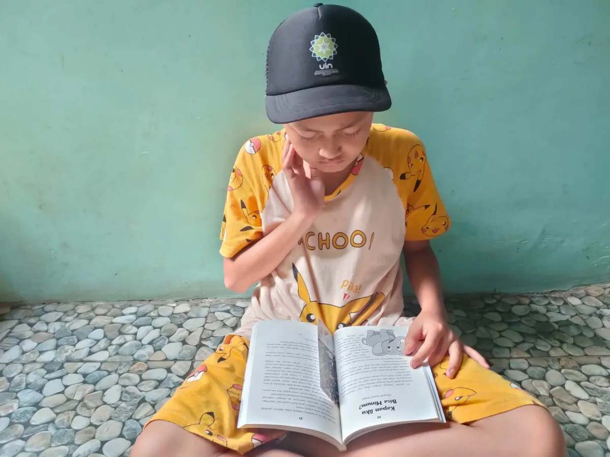 Aa Akil asyik membaca tulisan Persahabatan Kelinci dan Kura-Kura yang dimuat dalam buku Serunya Dunia Fabel (Sumber: Istimewa | Foto: IBN GHIFARIE)