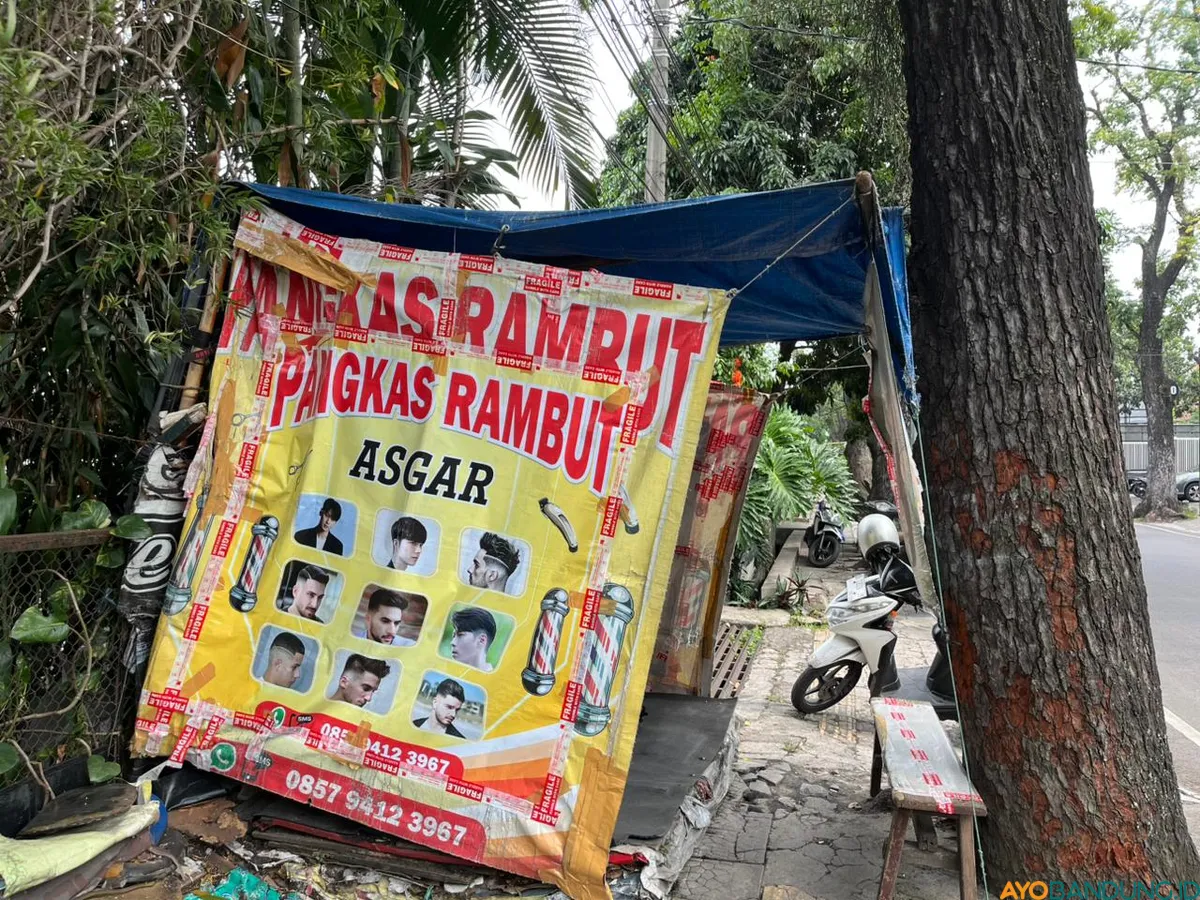 Di bawah pohon rindang di Jalan Malabar, lapak cukur sederhana tetap setia melayani pelanggan meski suasana tak seramai dulu. (Sumber: ayobandung.id | Foto: Ilham Maulana)