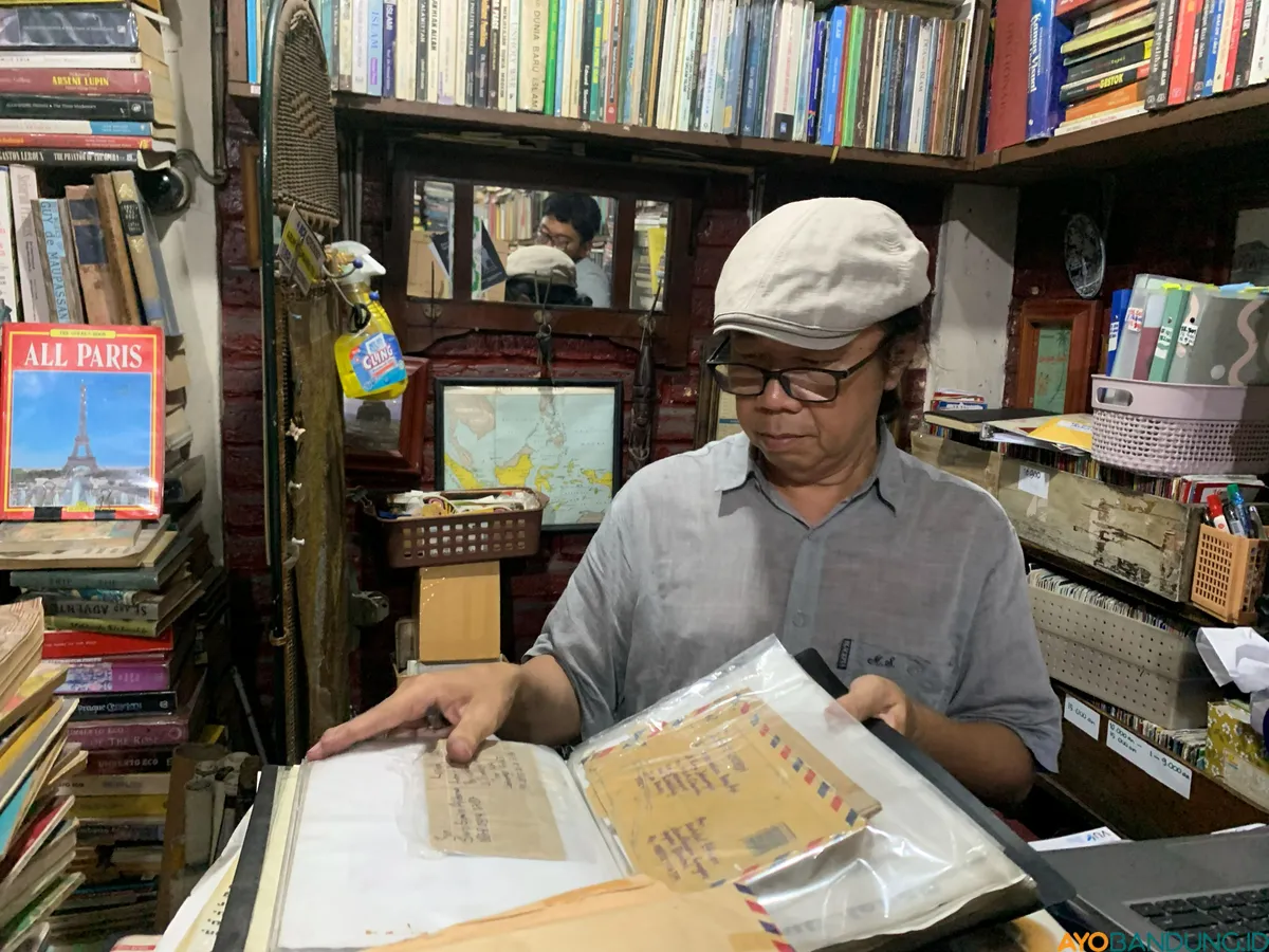 Anton Solihin menunjukkan salah satu koleksi buku di Perpustakaan Batu Api, Jatinangor. (Sumber: ayobandung.id | Foto: Halwa Raudhatul)