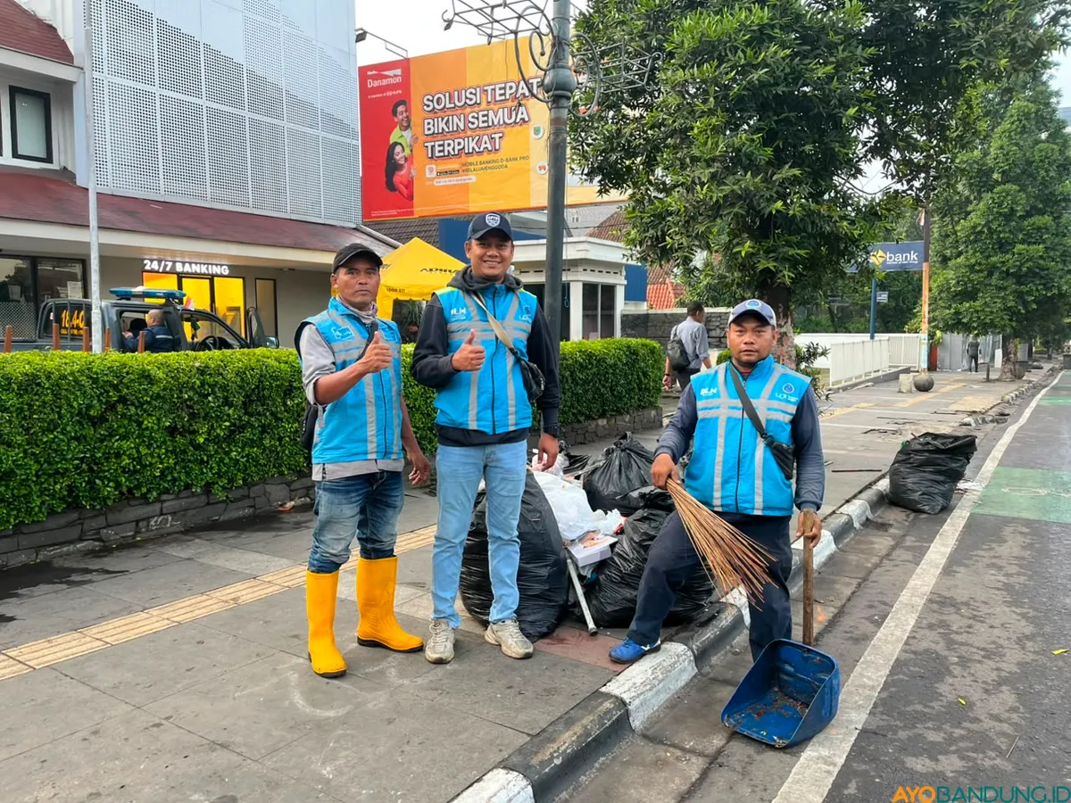 Ari Aldian bersama rekannya mulai membersihkan sisa sampah bekas konvoi Persib di kawasan Cikapayang sejak pagi buta (Sumber: ayobandung.id | Foto: Ilham Maulana)