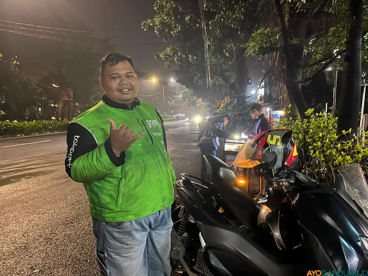 Tias, pengemudi ojol asal Cimahi, harus menghadapi macet dan jalan ditutup saat euforia kemenangan Persib berlangsung. (Sumber: ayobandung.id | Foto: Ilham Maulana)