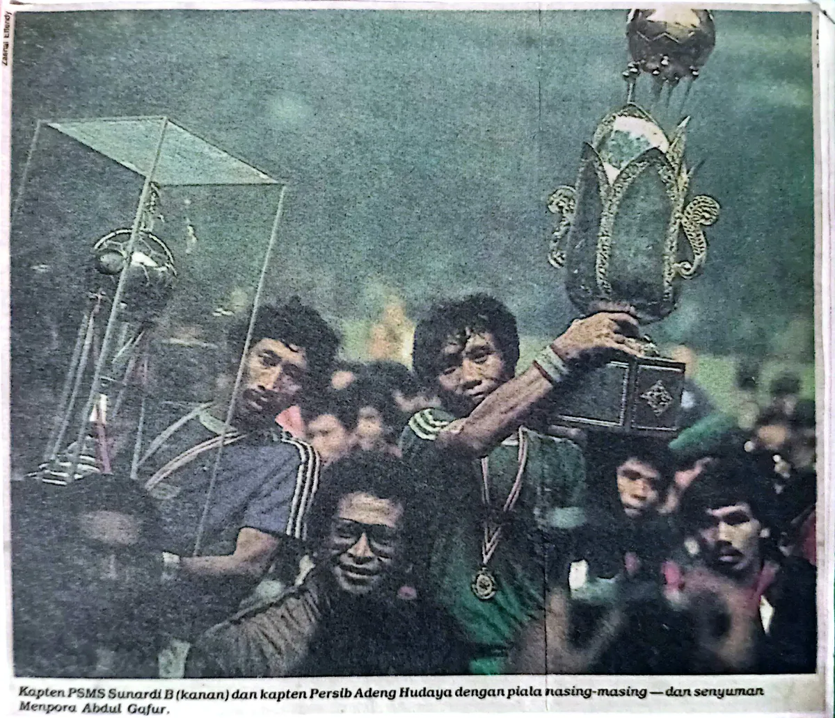 Kapten Persib Adeng Hudaya dan kapten PSMS Medan mengangkat Piala Juara Divisi Utama Perserikatan 1985. (Sumber: kliping dari tabloid olahraga BOLA edisi Februari 1983 | Foto: koleksi Kin Sanubary)
