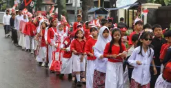 Sejumlah siswa SD Negeri 067 Nilem dengan didampingi guru dan orang tua mengikuti karnaval merah putih saat melintas di Jalan Nilem, Kota Bandung, Kamia 14 Aguatus 2025. (Sumber: Ayobandung.id | Foto: Irfan Al-Faritsi)