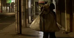 Seorang tunawisma menyusuri lorong Pasar﻿ pada malam hari (29/10/25) dengan memanggul karung besar di Jln. ABC, Braga, Sumur Bandung, Kota Bandung. (Foto: Rajwaa Munggarana)