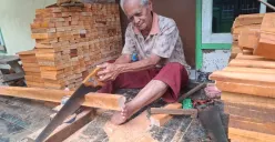 Abah Alek memotong papan kayu menggunakan gergaji tangan, proses awal pembuatan sikat. (Foto: Lamya Fatimatuzzahro)