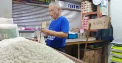 Rahmat Kurnia (52) tengah menyiapkan sekantong plastik beras untuk pembeli di Pasar Kosambi, Kota Bandung. (Sumber: ayobandung.id | Foto: Gilang Fathu Romadhan)