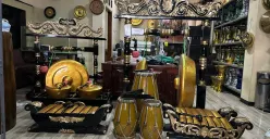 Pengrajin Giri Purwa Seni menampilkan seperangkat alat musik tradisional berwarna keemasan di ruang pamer Giri Purwa Seni, Jl. Soekarno Hatta No. 425, Desa Cigereleng, Astana Anyar, Karasak, pada Senin, 10 November 2025. (Sumber: Dokumentasi Penulis)