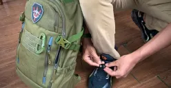 Dyvo Xavier Muhamad Yandi Putra sedang mengikat tali sepatunya sambil membawa tas ransel Cartenz Tactical di sampingnya .(Foto: Patricia Avrilia Rolina)
