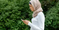 Ilustrasi muslimah sedang memandang smartphone. (Sumber: Pexels | Foto: MART PRODUCTION)