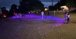 Anak-anak berlarian di atas sorot lampu yang menyapu rumput di Titik Kumpul–Backyard, Bandung, sebagai bagian dari aktivasi seni Sesar Lembang Kalcer dalam menyampaikan literasi mitigasi bencana secara ramah.