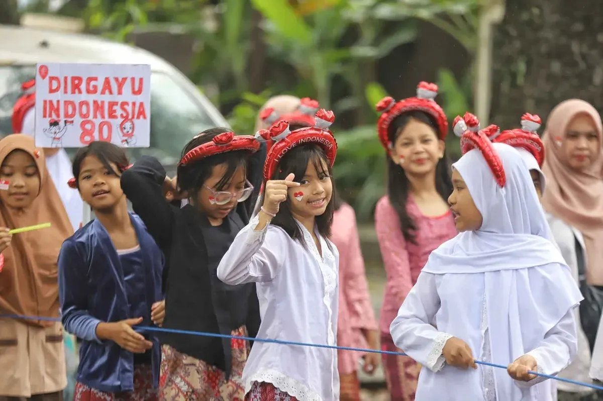 Siswa SD Negeri 067 Nilem dengan didampingi guru dan orang tua mengikuti karnaval merah putih saat melintas di Jalan Nilem, Kota Bandung, Kamis 14 Agustus 2025. (Sumber: ayobandung.com | Foto: Irfan Al-Faritsi)