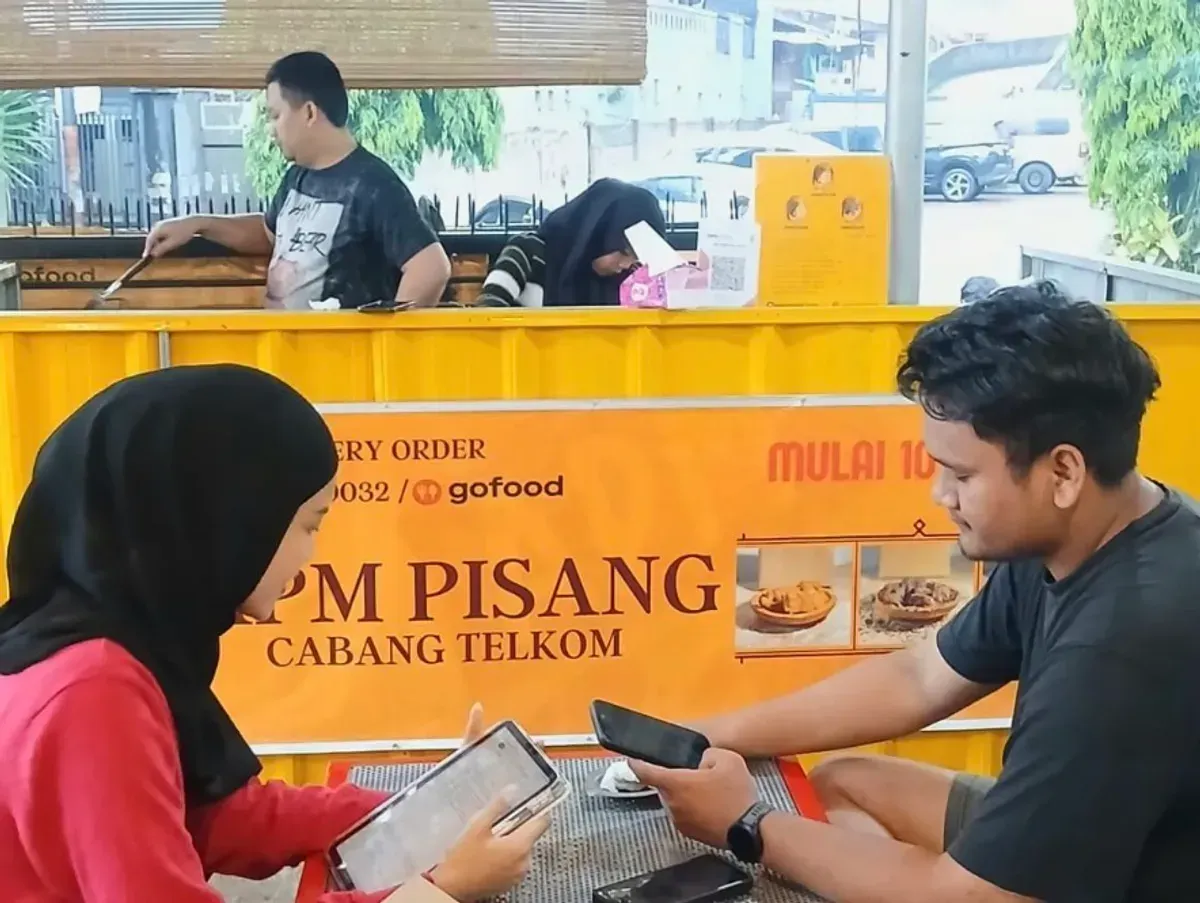 Penulis sedang mewawancarai narasumber, Haqqi, owner APM Pisang di depan outlet cabang Telkom. (Sumber: Dokumentasi Penulis | Foto: Wardah)
