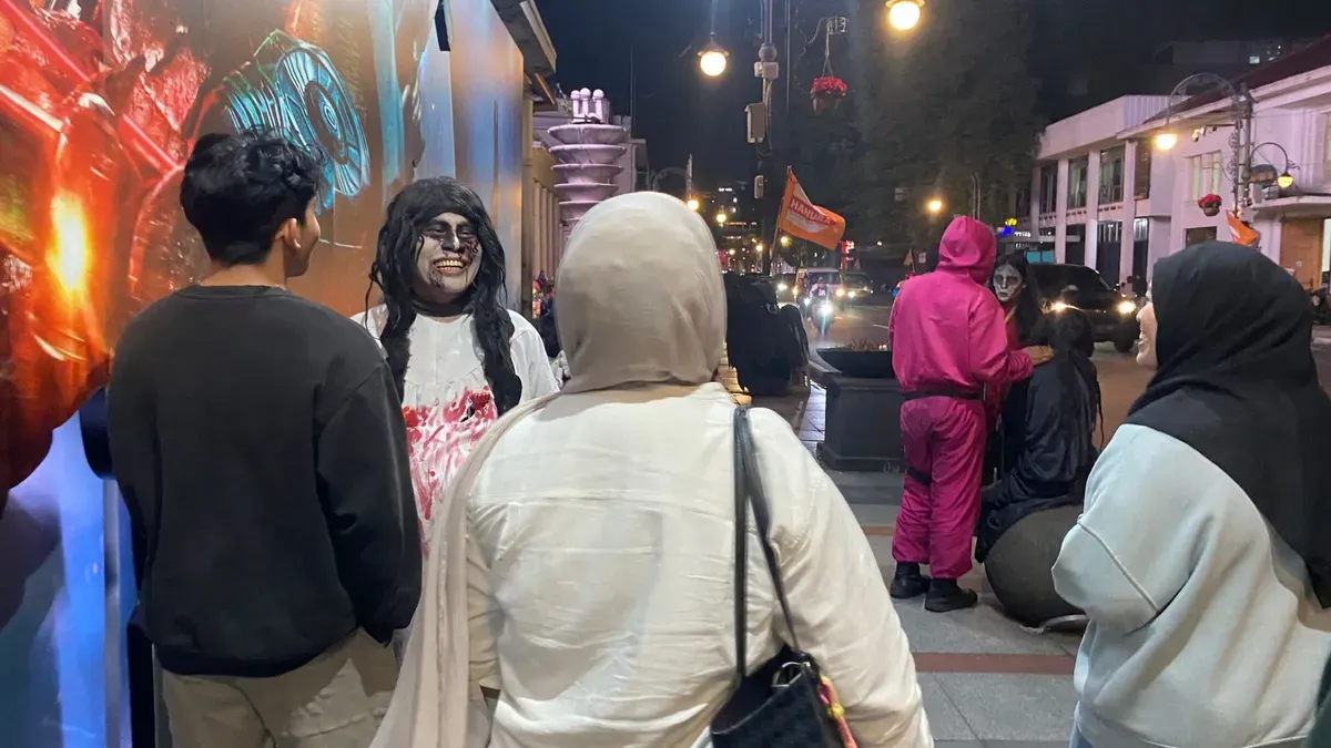 Keramaian di kawasan wisata malam Bandung memperlihatkan interaksi tidak nyaman antara pengunjung dan pengamen memaksa, 02/12/2025. (Foto: Hakim)