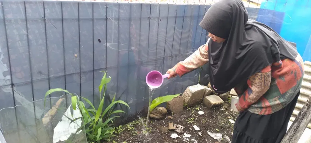 Salah seorang warga sedang menyiram kuburan Tembuni cucunya yang dibantu oleh Ika pada tahun 2019 lalu di Desa Pagerwangi, Kecamatan Lembang, Kabupaten Bandung Barat. (3/11/2025) (Sumber: Dokumentasi Penulis | Foto: Azzahra Nadhira)