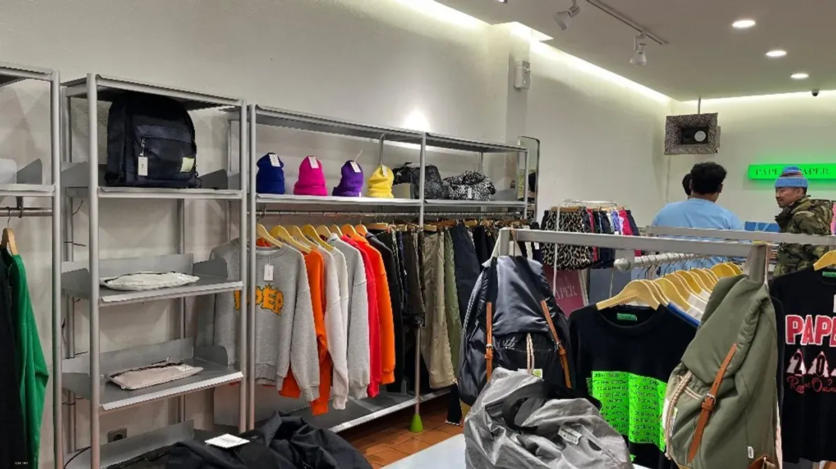 Pengunjung PAPER menikmati suasana toko yang menampilkan koleksi busana kasual berwarna mencolok pada rak dan gantungan pakaian (28/10/2025) (Foto: Malik)