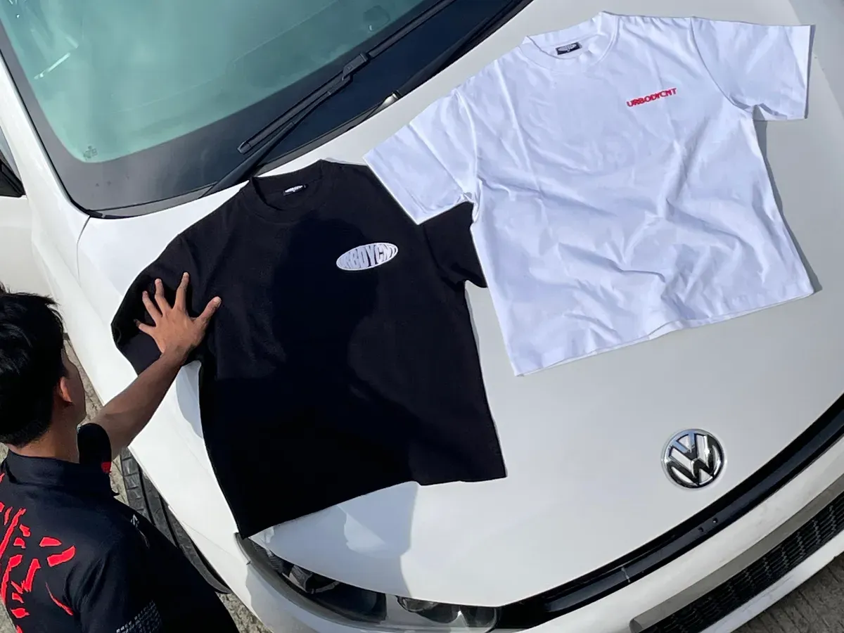 Tim urbodycount menata koleksi kaos edisi terbaru di atas mobil sebagai bagian dari proses pemotretan produk di Buahbatu Square Jl.Apel 1 NO.18, Bandung, Jawa Barat, Selasa (4/11/2025) (Sumber: Rahma Dewi | Foto: Rahma Dewi)