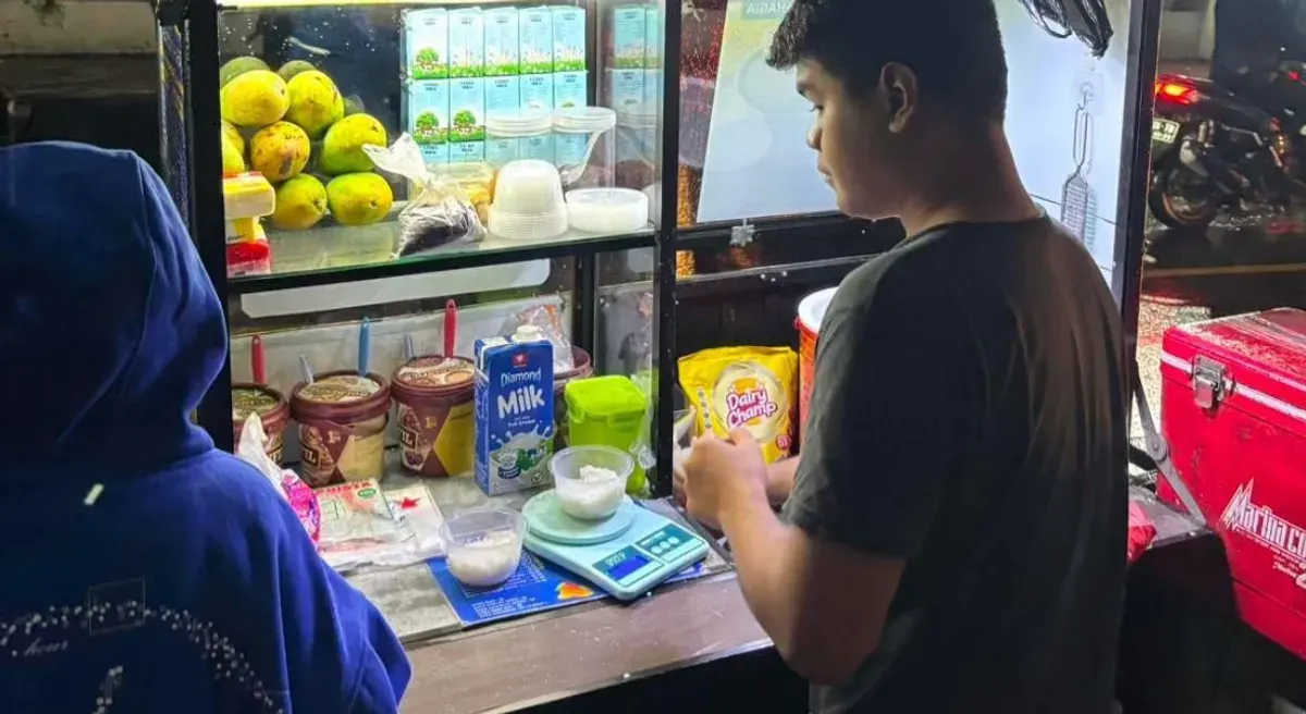 Pedagang menyiapkan ketan pesanan pembeli di pinggir jalan pada sore hari setelah hujan (31/10/2025) (Foto: Hanina Aulia Saffana)