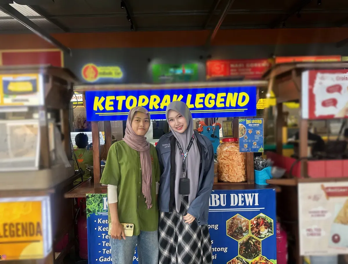 Gambar 1.1 Karyawan Ketoprak Legend Bu Dewi menyambut pembeli di depan gerobak biru khas mereka (28/10/2025). (Sumber: Dokumentasi pribadi penulis | Foto: Syakirah Salsabila)