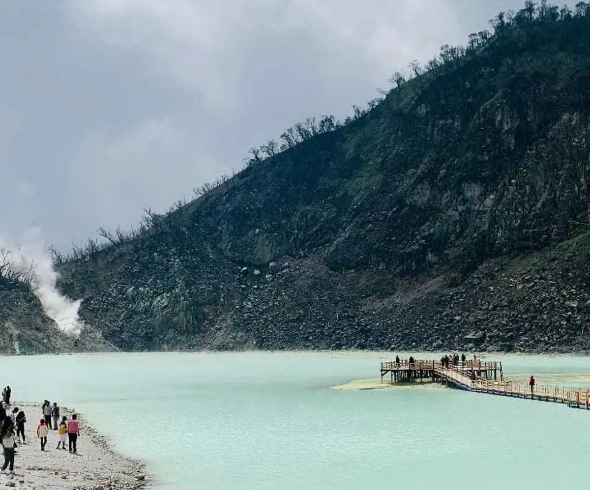Pemandangan di Kawasan kawah putih, terlihat danau berwarna biru muda di antara tebing berbatu, dan aktivitas pengunjung di dermaga. (Sumber: Dokumentasi Penulis| Foto: Aria Huara Nasywa)